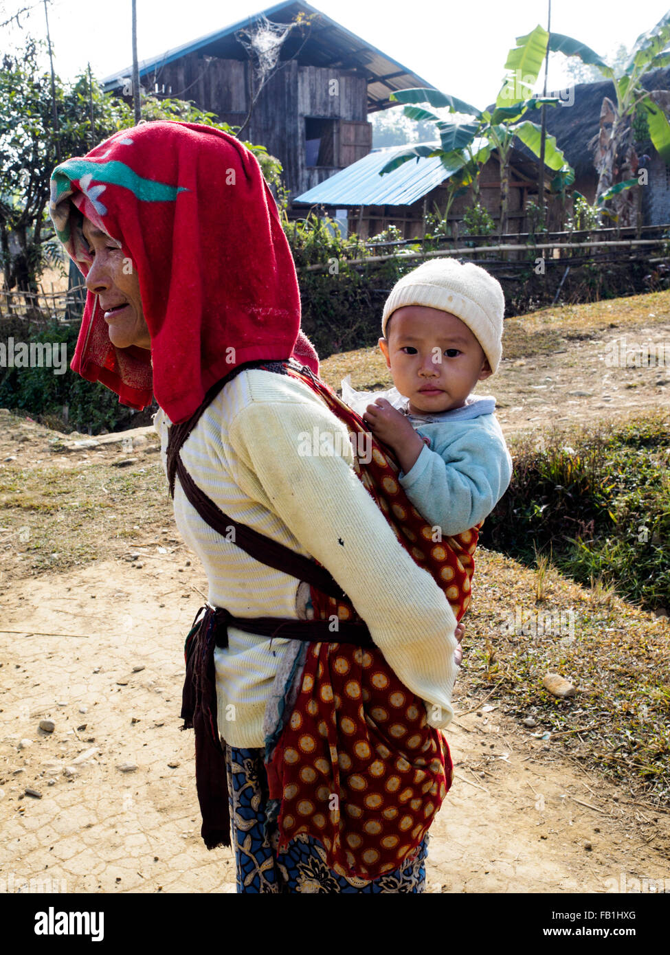 A woman in Putao carries a baby on her back. Stock Photo