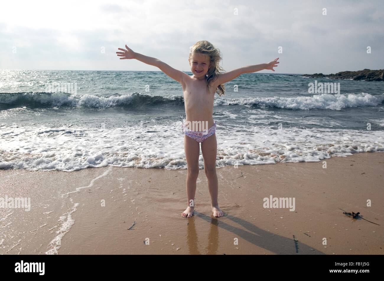 Portrait of girl with arms open on beach at Sardinia, Italy Stock Photo
