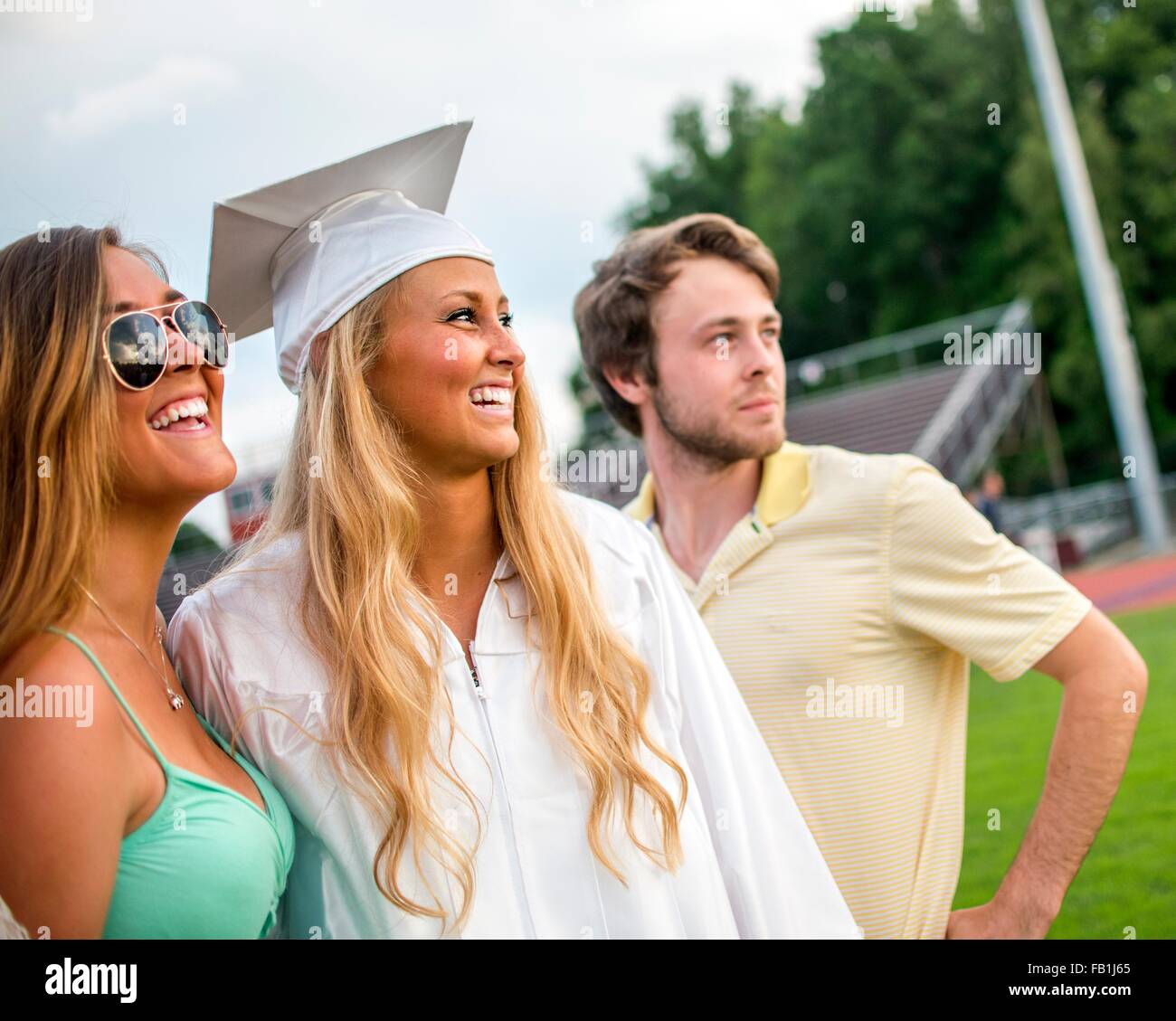 Young female graduate with sister and brother at graduation ceremony Stock Photo