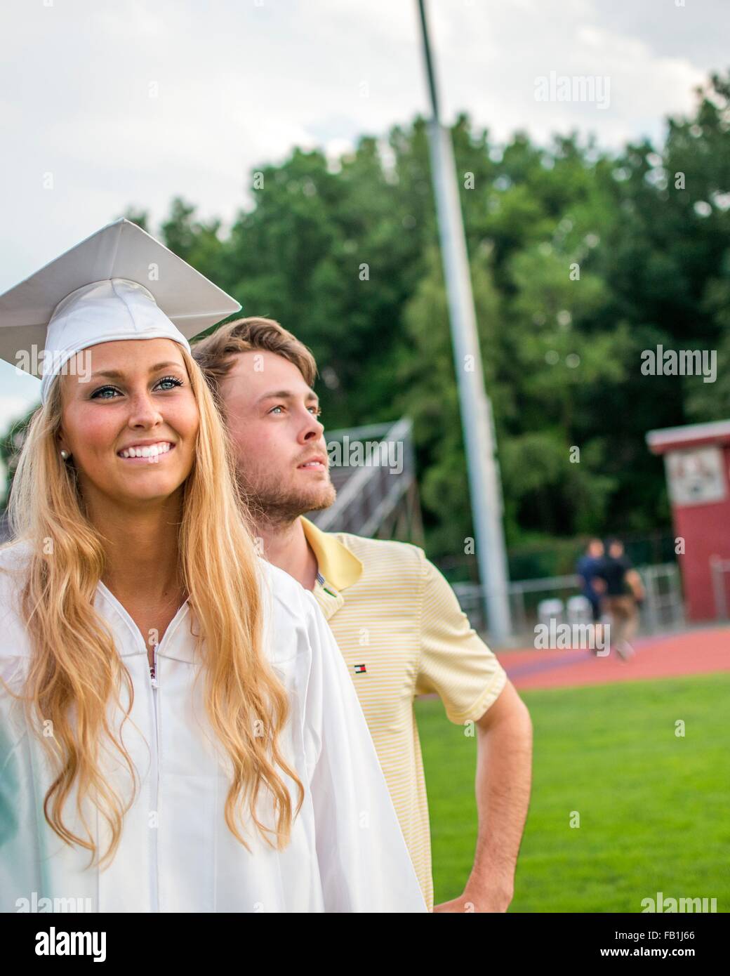 Young female graduate and brother at graduation ceremony Stock Photo