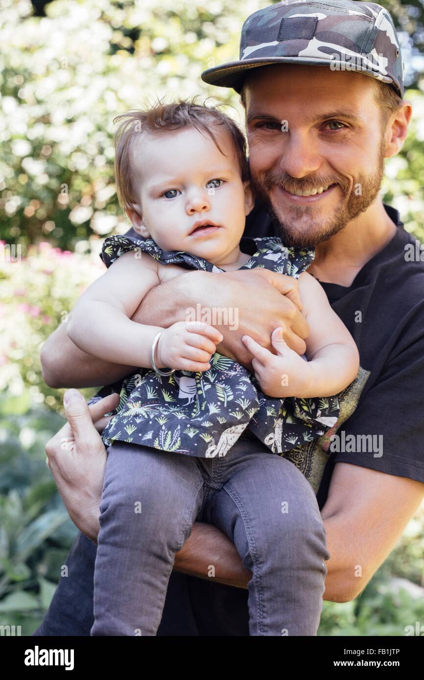 Portrait of mid adult man carrying baby daughter in woodland Stock Photo