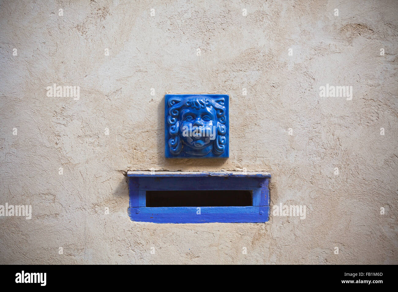 Plaster wall with blue decorative letter slot mailbox. Horizontal shot