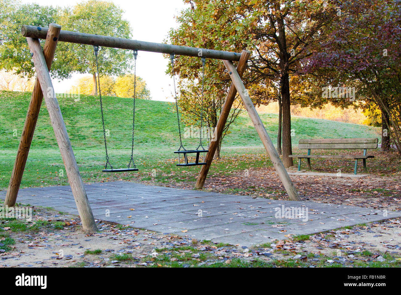 Swing and bench in a park with fallen leaves Stock Photo