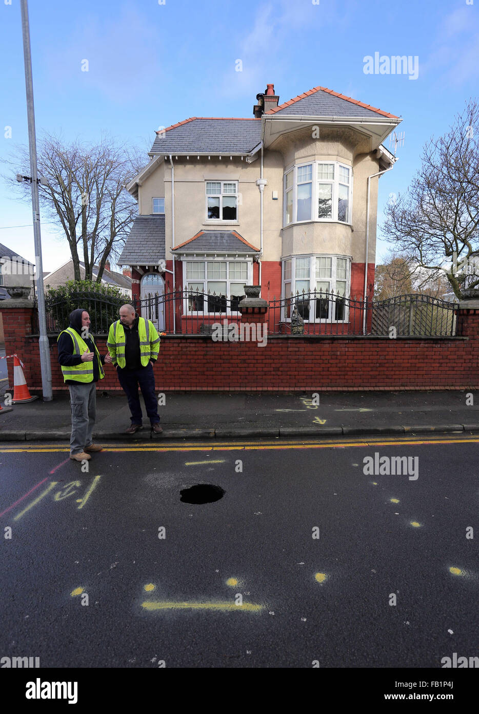 Neath, UK. Thursday 07 January 2016 Council officials by the sinkhole in Cimla Road, Neath Re: A sinkhole up to 10ft deep has appeared in Neath. south Wales, leading to the closure of a main road. Police have sealed off Cimla Road, in Neath, following the discovery at the bottom of Cimla Hill. South Wales Police and Neath Port Talbot council workers are currently at the scene assessing the damage and preparing to carry out emergency repairs. Credit:  D Legakis/Alamy Live News Stock Photo