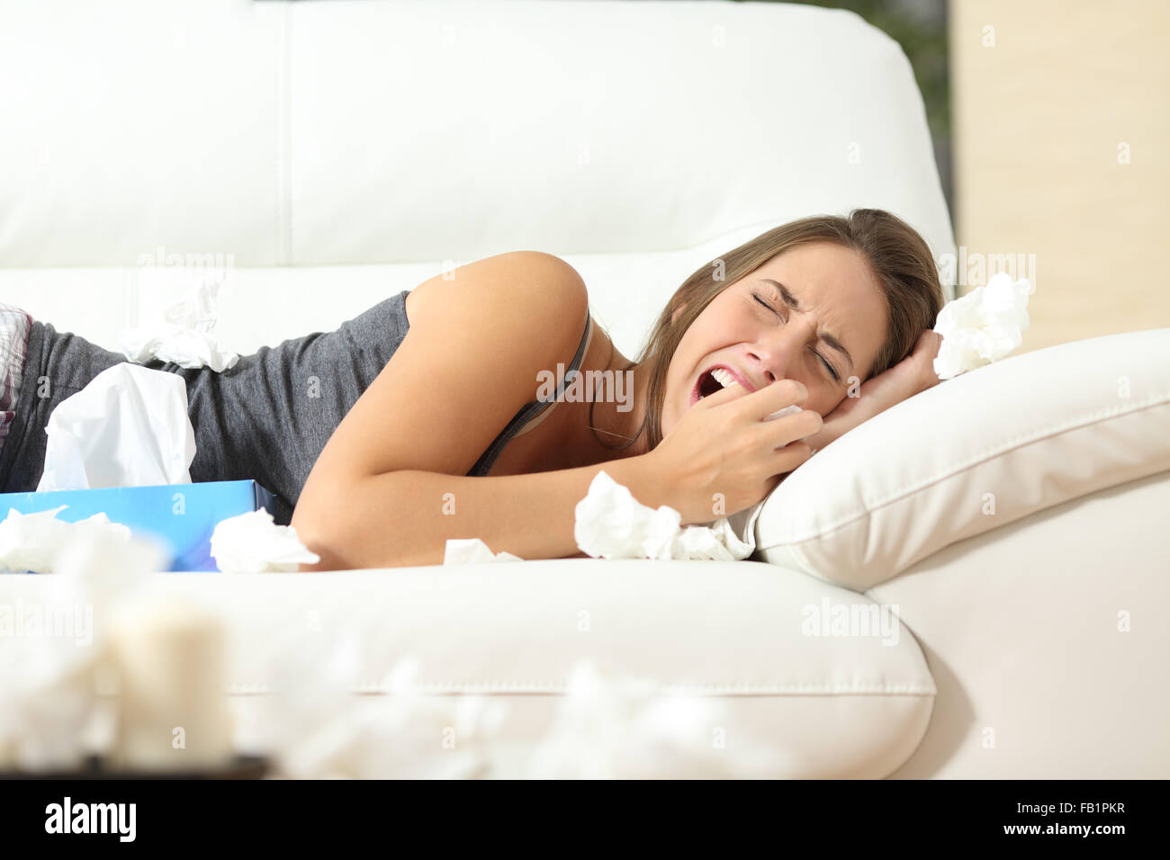 Girl crying desperately lying on a couch at home with a lot of wipes Stock Photo