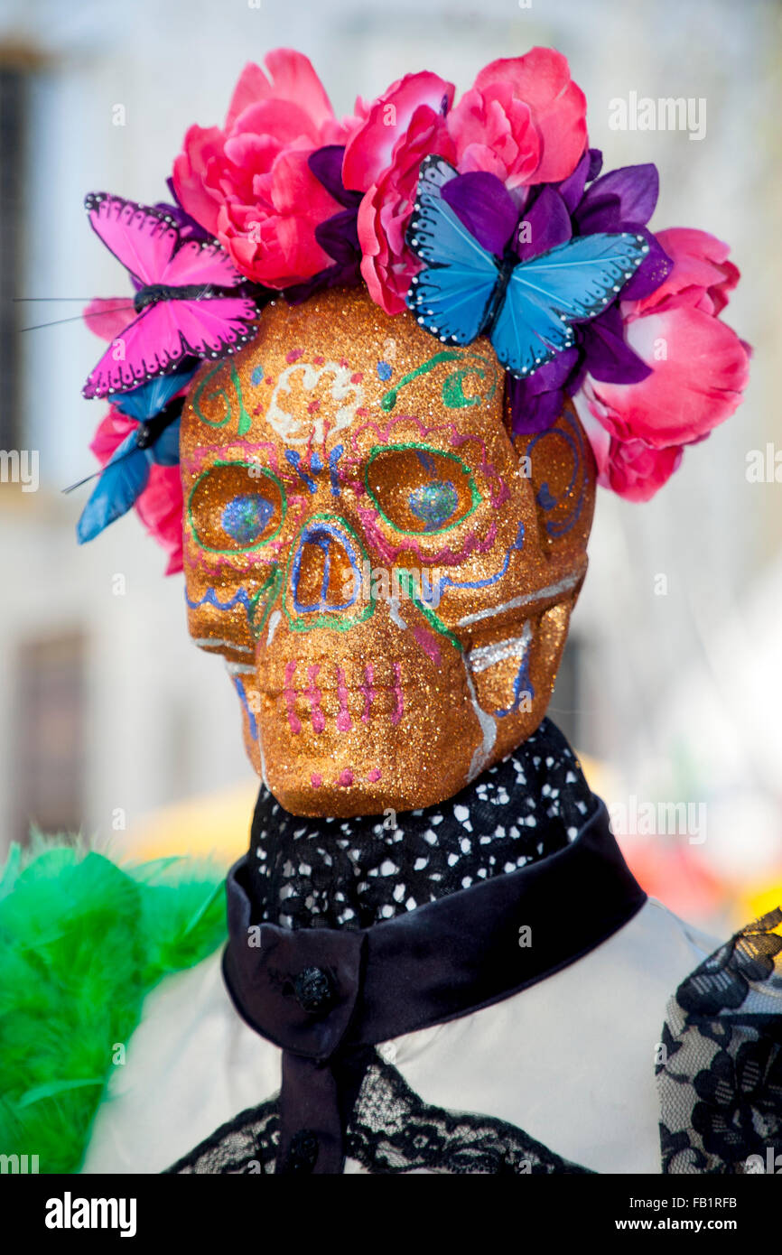 A common symbol of the Mexican holiday Day of the Dead  or Dia de Muertos is the skull (in Spanish calavera), which celebrants represent in masks, called calacas (colloquial term for skeleton). Note decorative flowers and butterfly. The holiday focuses on Stock Photo