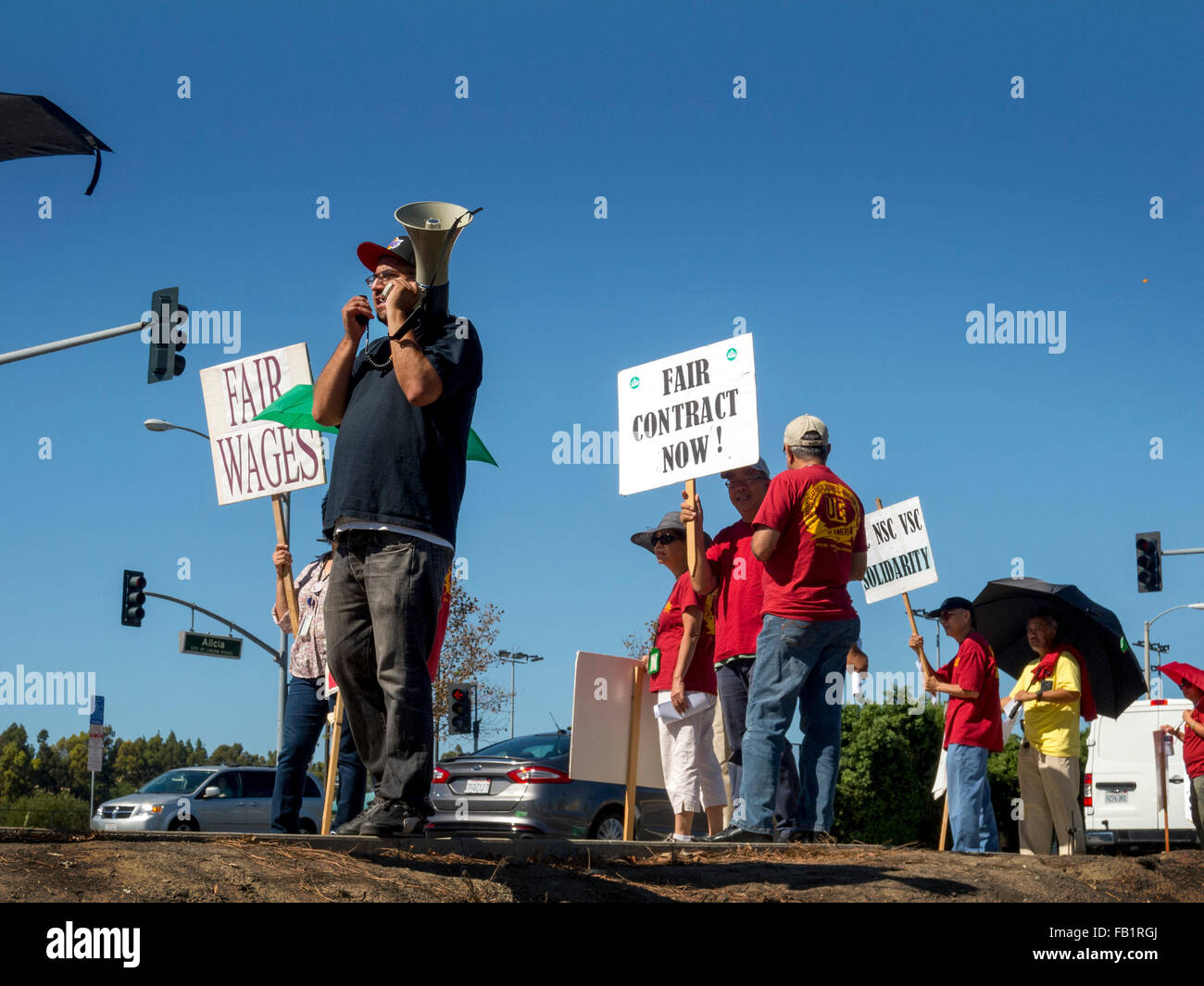 Multiracial striking electrical union workers picket a US Government building in Laguna Niguel, CA, protesting lack of scheduled salary increases. Note picket organizer with bull horn. Stock Photo