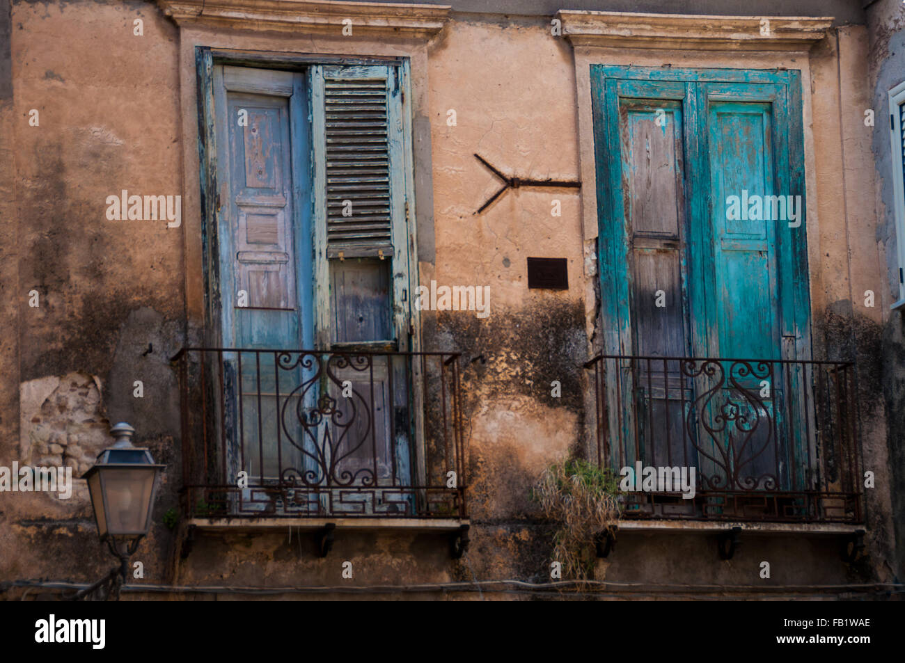 Old Italian stone house front with green shutter blinds and balcony in