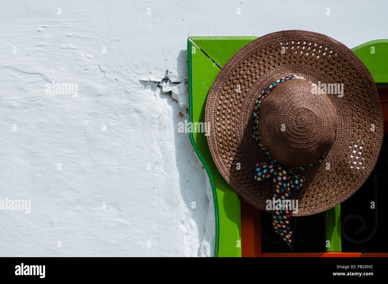 Brown straw hat hanging on colorful doorway Stock Photo