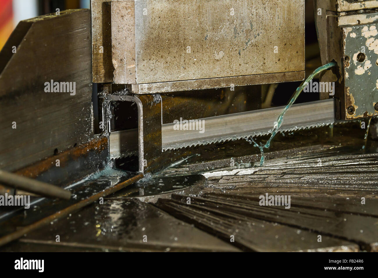 Cutting steel tubing on a metal band saw with green coolant flowing