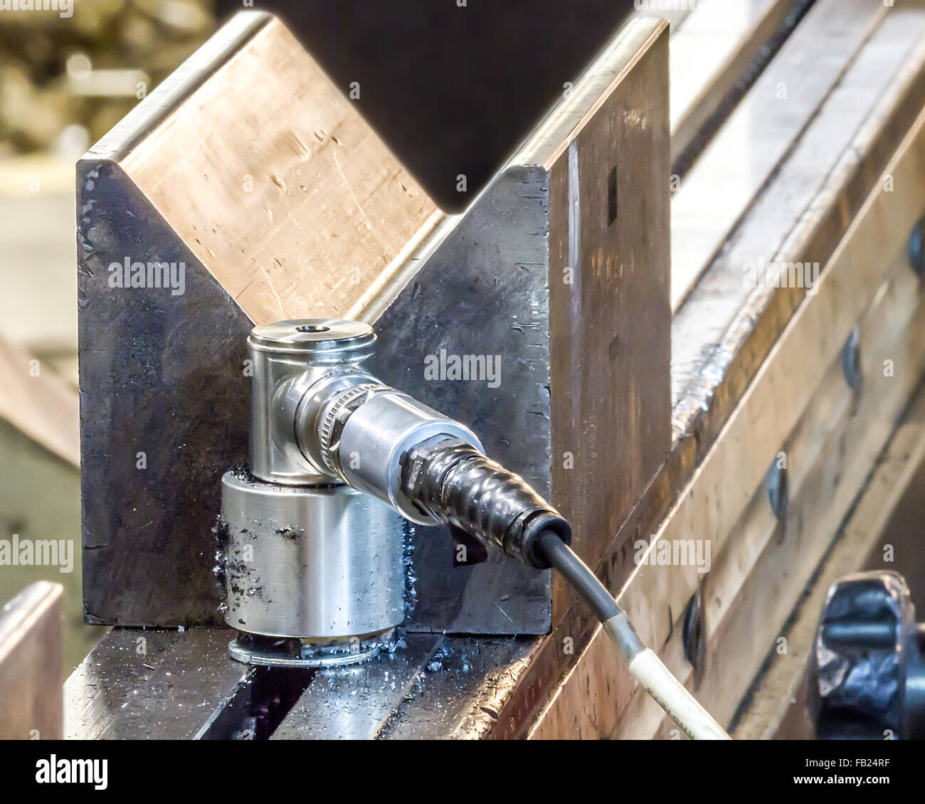 Vibration sensor covered in magnetic steel shavings in front of ninety degree block and die for bending metal on a press Stock Photo