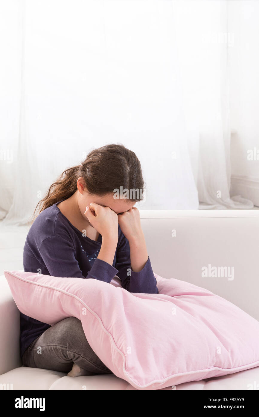 Teen girl in depression hugging pink pillow Stock Photo