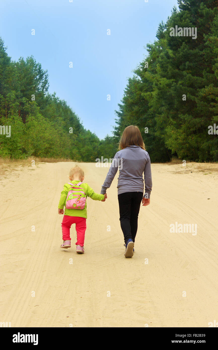 little sisters go on a forest road holding hands Stock Photo