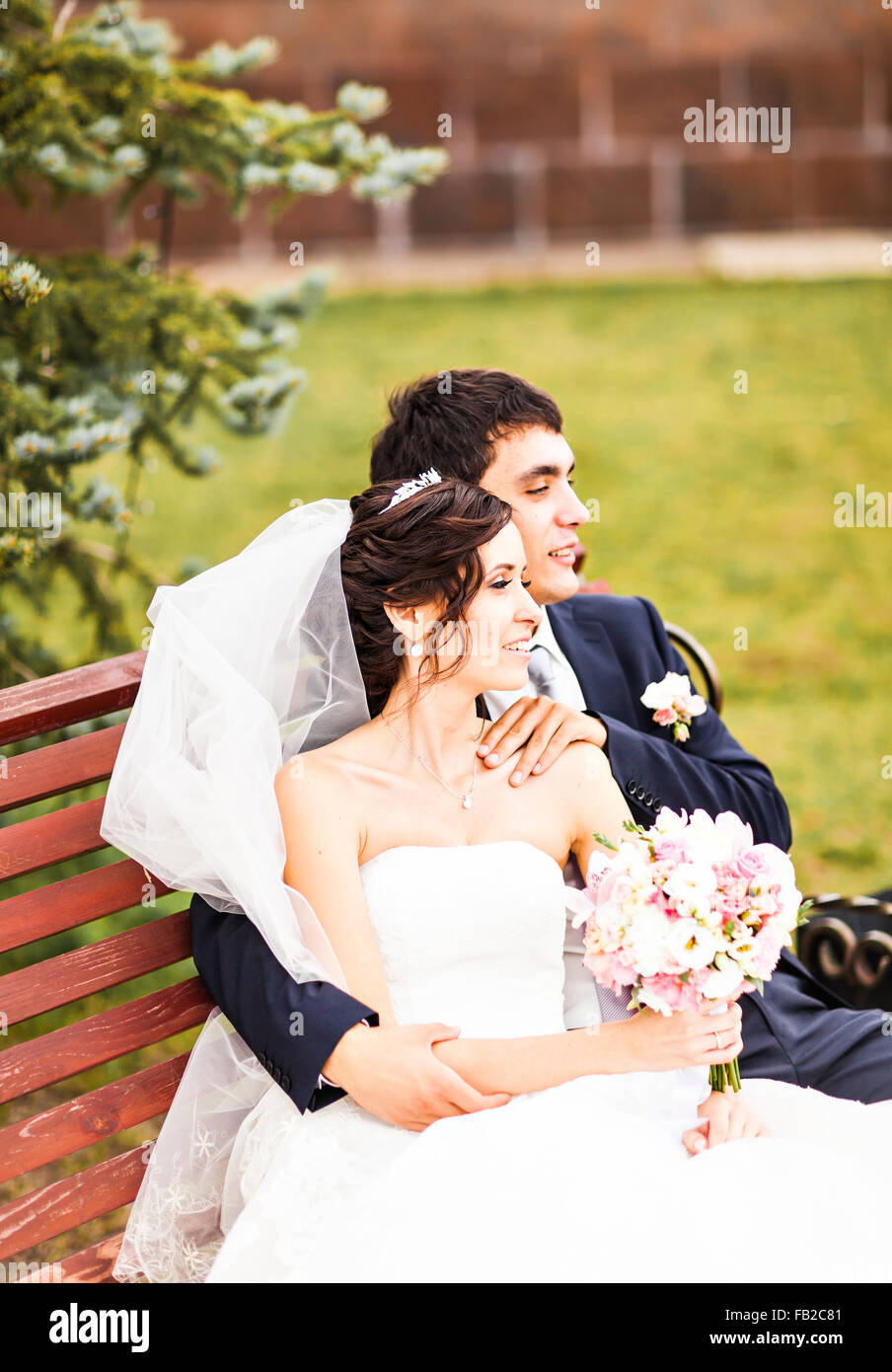 The bride and groom sitting on a bench in the Park Stock Photo - Alamy