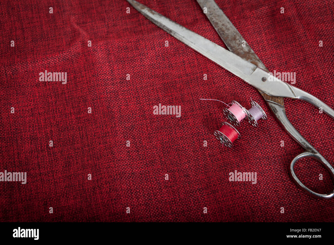 to sew a red cloth with scissors and thread Stock Photo