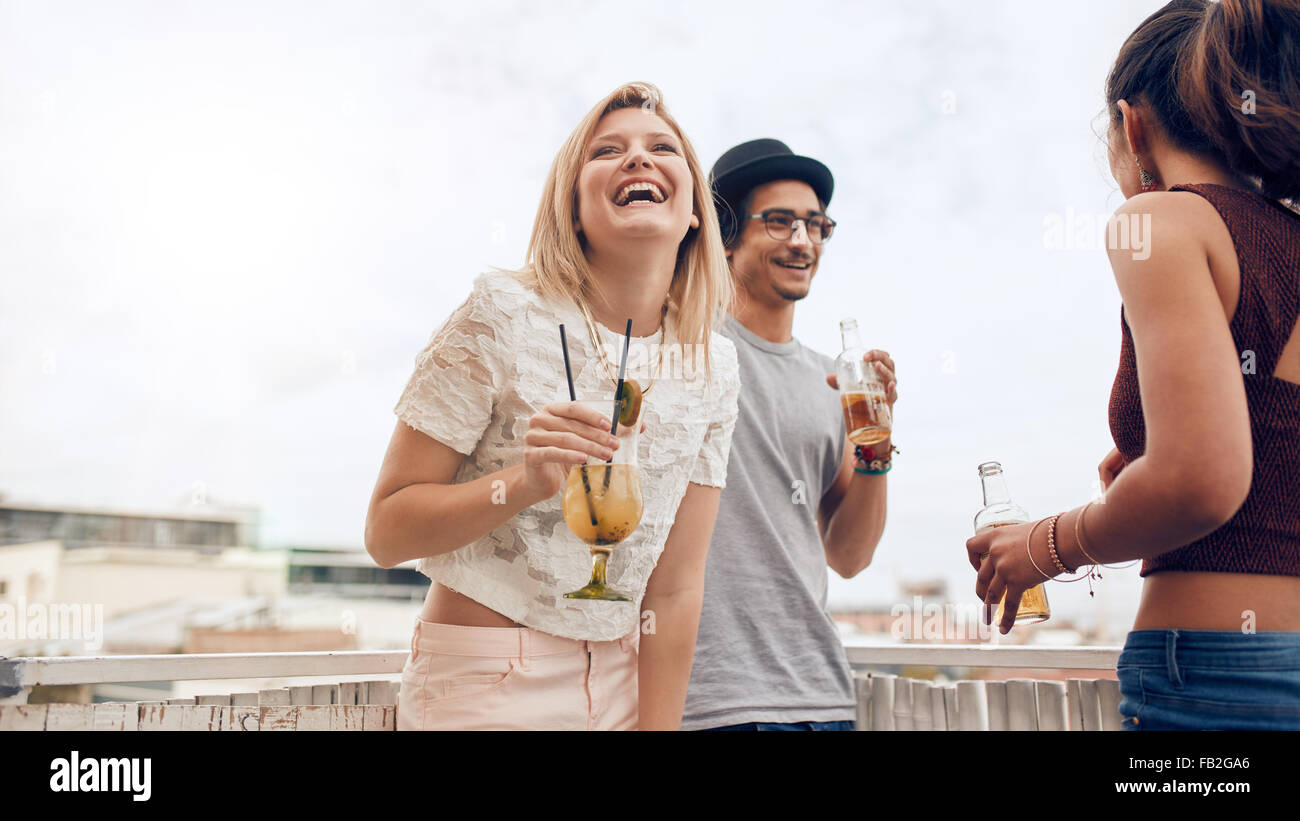 Portrait of cheerful young woman enjoying party with her friends. Young people having fun at rooftop party. They are laughing an Stock Photo