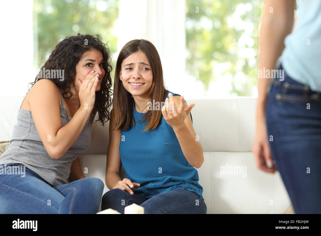 Two gossip friends criticizing another woman at home Stock Photo