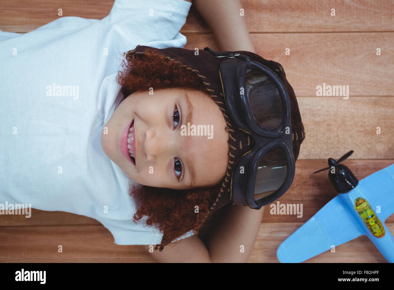 Smiling girl laying on the floor wearing aviator glasses and hat Stock Photo