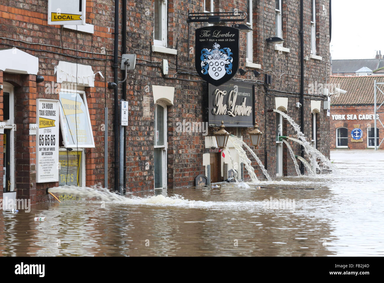 Water pours out of a flooded pub in York, North Yorkshire, UK, after both the River Ouse and Foss burst their banks. Stock Photo