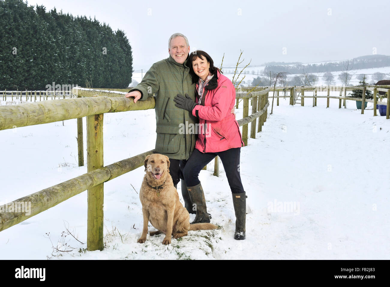 Middle aged couple walking their dog in a winter countryside Stock Photo