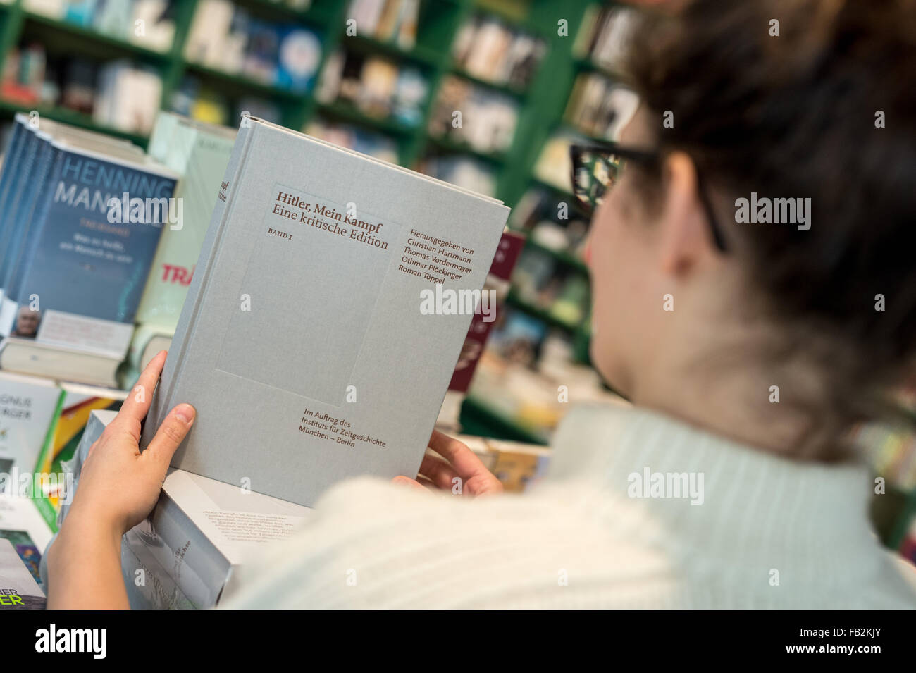 Munich, Germany. 8th Jan, 2016. ILLUSTRATION - Book seller Marie Katzlinger takes the first of two volumes of the annotated edition of 'Hitler, Mein Kampf - A criticial edition' into her hand in the Lehmkuhl bookshop . The 'Institut fuer Zeitgeschichte' (Institute for contemporary history) is presenting on the day of publication, the annotated edition of the 1924 original publication of the inflammatory pamphlet 'Mein Kampf', authored by national socialist dictator Adolf Hitler. Credit:  dpa picture alliance/Alamy Live News Stock Photo
