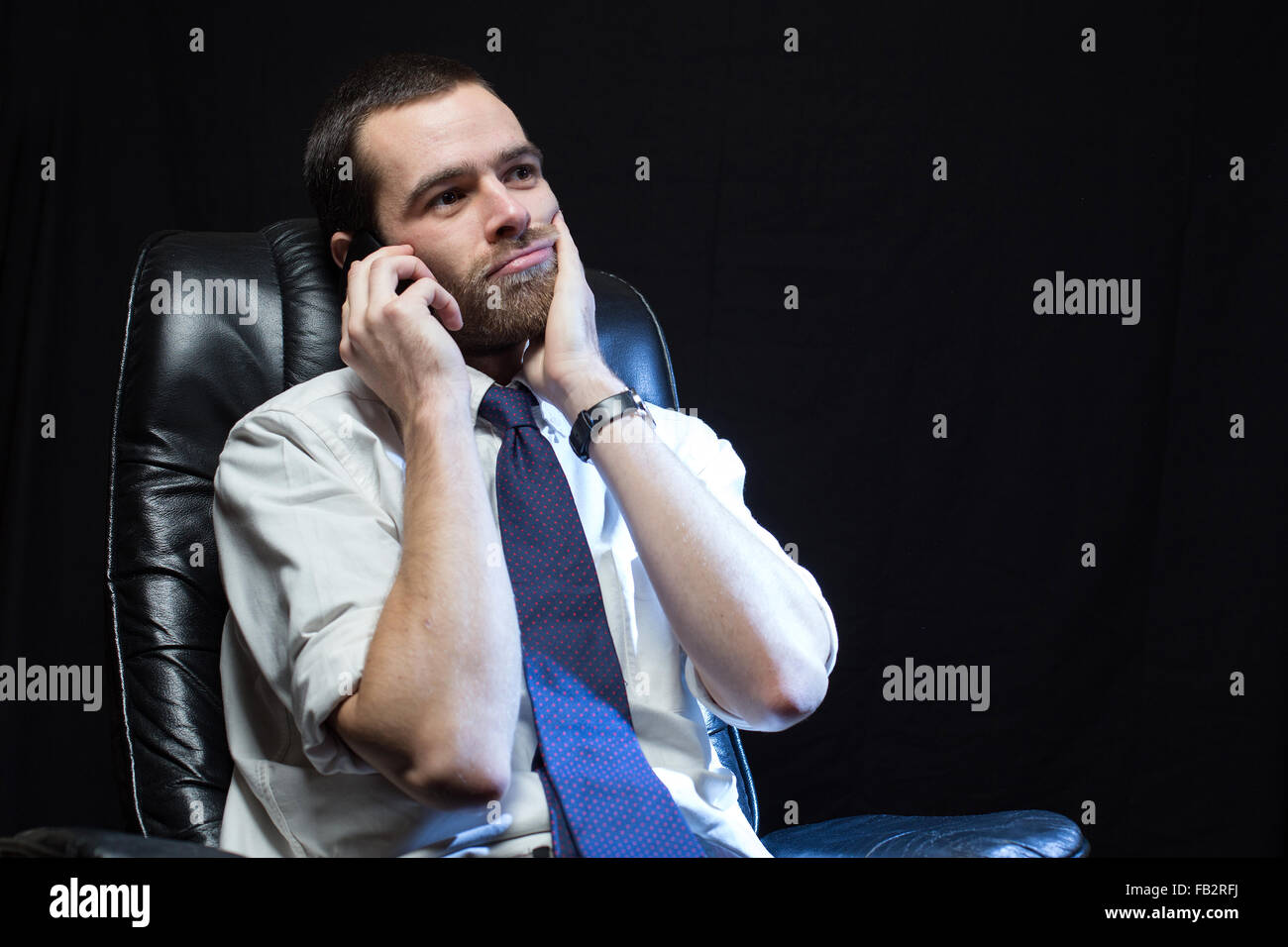 An office worker, wearing a shirt and tie, speaks on the phone. Stock Photo