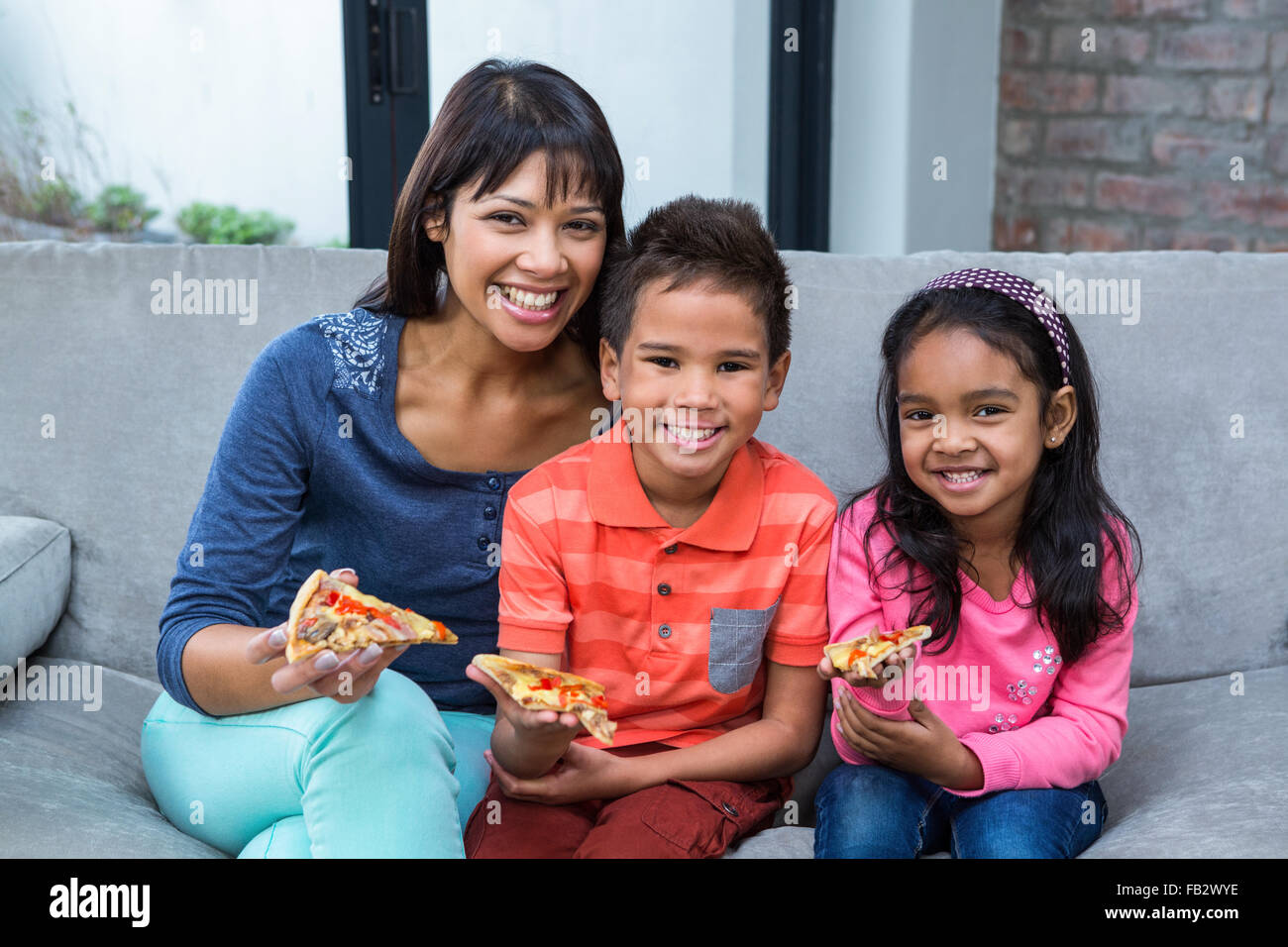 Happy  family eating pizza on the sofa Stock Photo