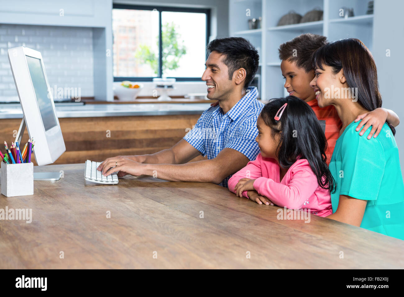 Happy family using computer in the kitchen Stock Photo - Alamy image.