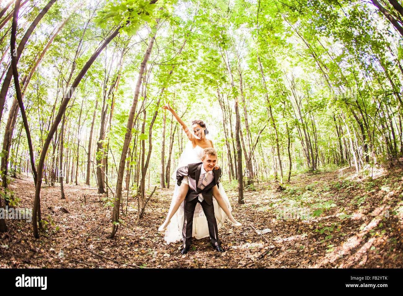 groom running away with bride on his back in park Stock Photo Alamy