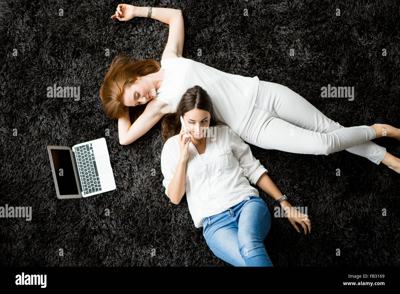 Young women laying on the carpet with laptop Stock Photo