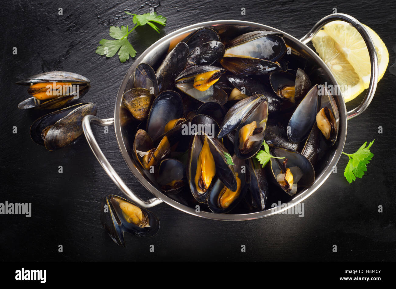 Boiled mussels in a cooking dish on a dark background. Top view Stock Photo