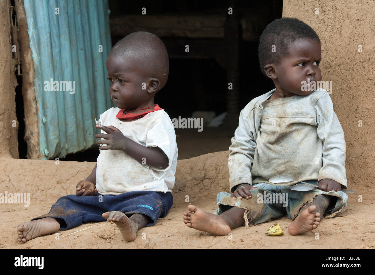Young undernourished children sitting outside their home in poor
