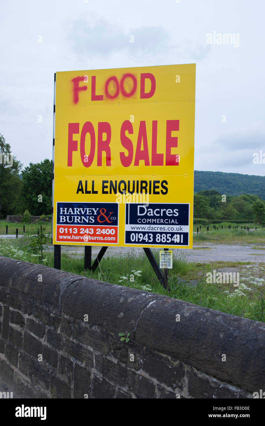 Irony, sarcasm, humour. Large sign advertising sale of land on floodplain - defaced and the word 'land' changed to 'flood.' Otley, England, GB, UK. Stock Photo