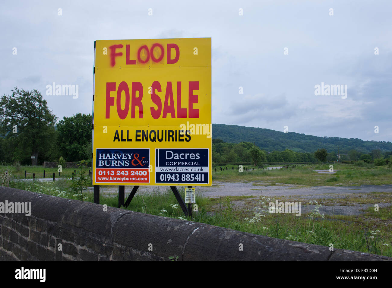 Irony, sarcasm, humour. Large sign advertising sale of land on floodplain - defaced and the word 'land' changed to 'flood.' Otley, England, GB, UK. Stock Photo