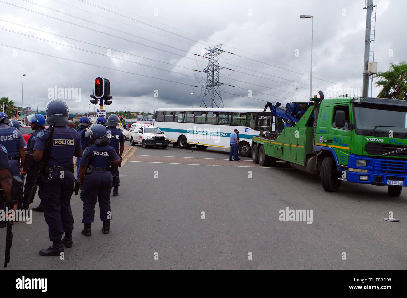 Durban, South Africa. 8th January, 2016. Riot police stand at an intersection while a tow truck removes a Durban municipal bust that was abandoned by striking bus drivers at an intersection on the Mangosuthu Highway in Durban's second largest township of Umlazi. The staff of the bus service have not been paid their slaries or bonuses for December, while some also claim that Tansnat CC, the company that manages the service for the municipality, has not paid their provident fund. Credit:  Giordano Stolley/Alamy Live News Stock Photo