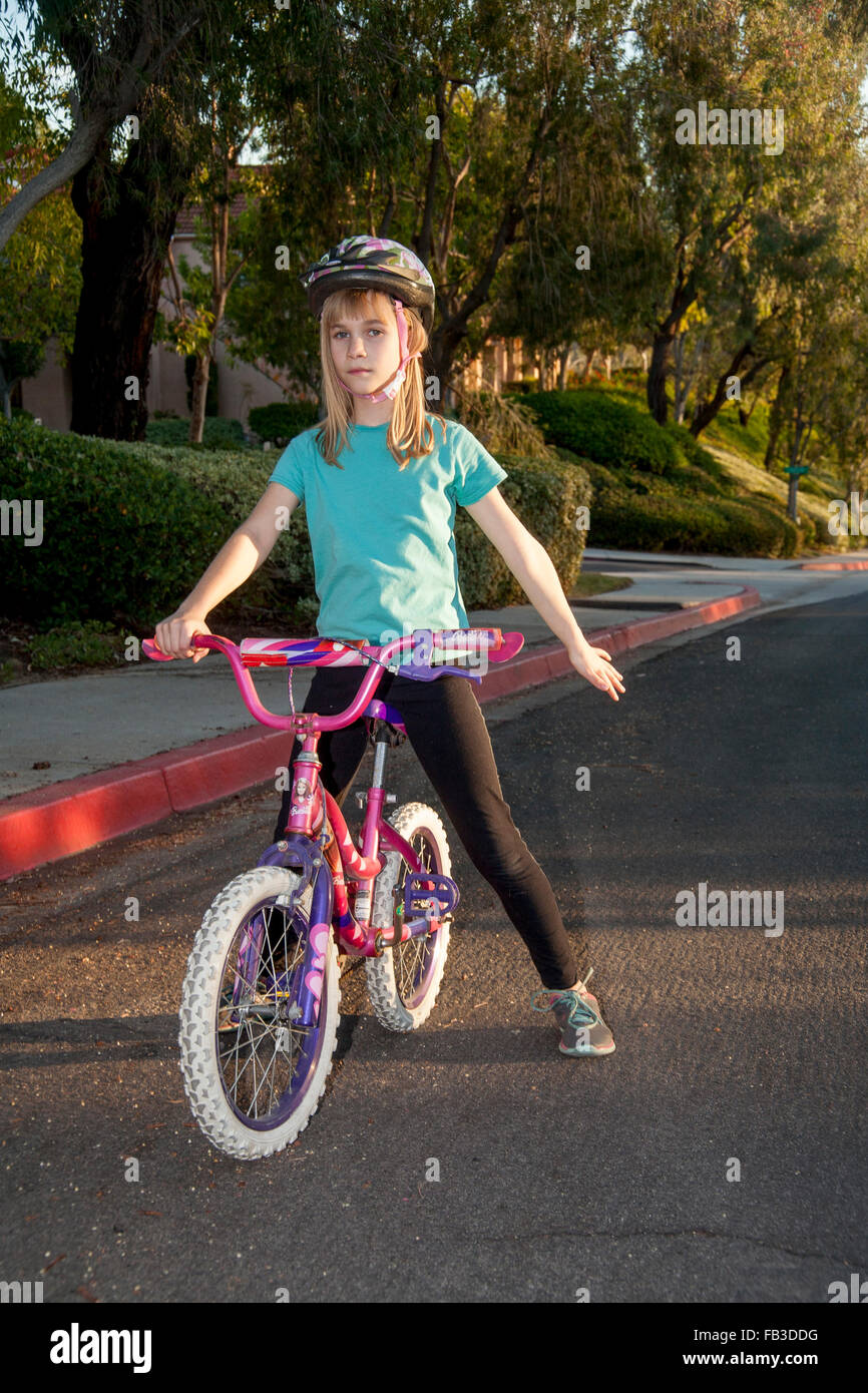A tween girl bicyclist signals a stop using her left arm on a street in Lake Forest, CA MODEL RELEASE Stock Photo