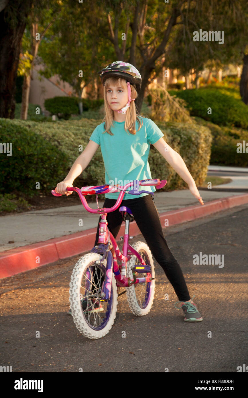 A tween girl bicyclist signals a stop using her left arm on a street in Lake Forest, CA. MODEL RELEASE Stock Photo