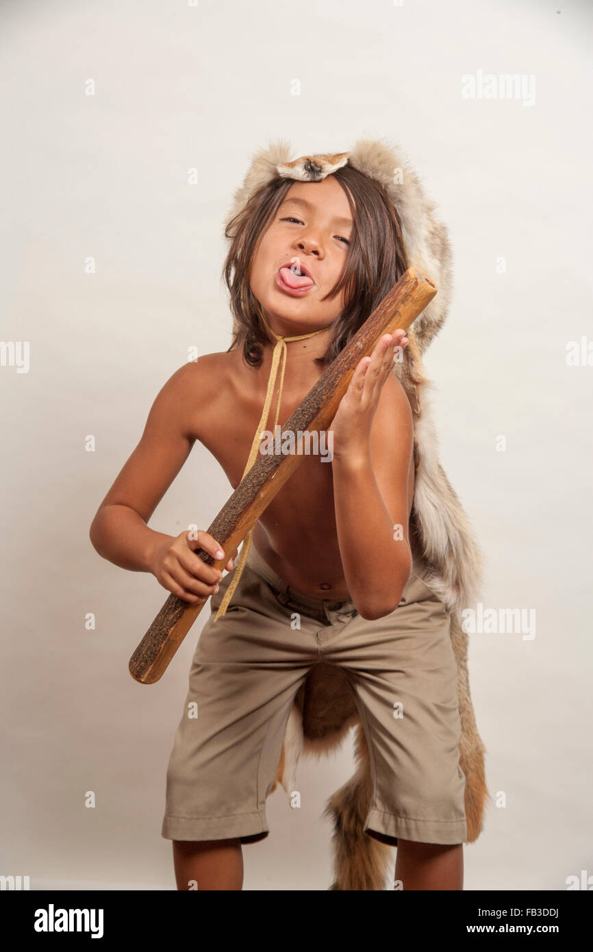 A Native American boy member of the Acjachemen tribe plays the clapper stick, a primitive percussion musical instrument. Note coyote head costume appropriate for male tribal members.MODEL RELEASE MODEL RELEASE Stock Photo