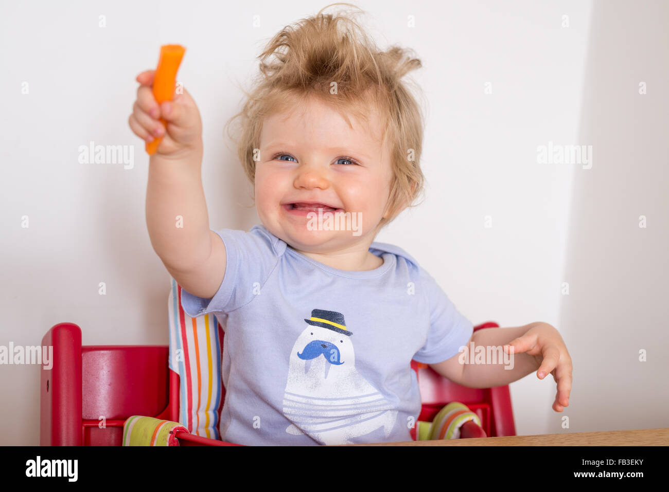 Happy one year old baby eating carrots Stock Photo
