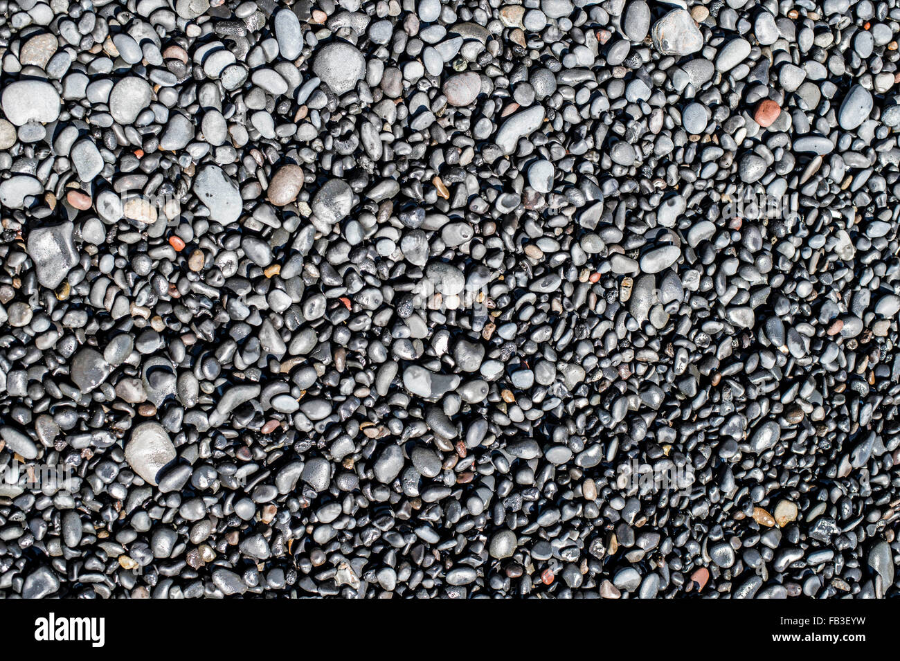 Small basalt rocks that make up the famous black sand beaches along the popular Icelandic coastline near Vik. Stock Photo