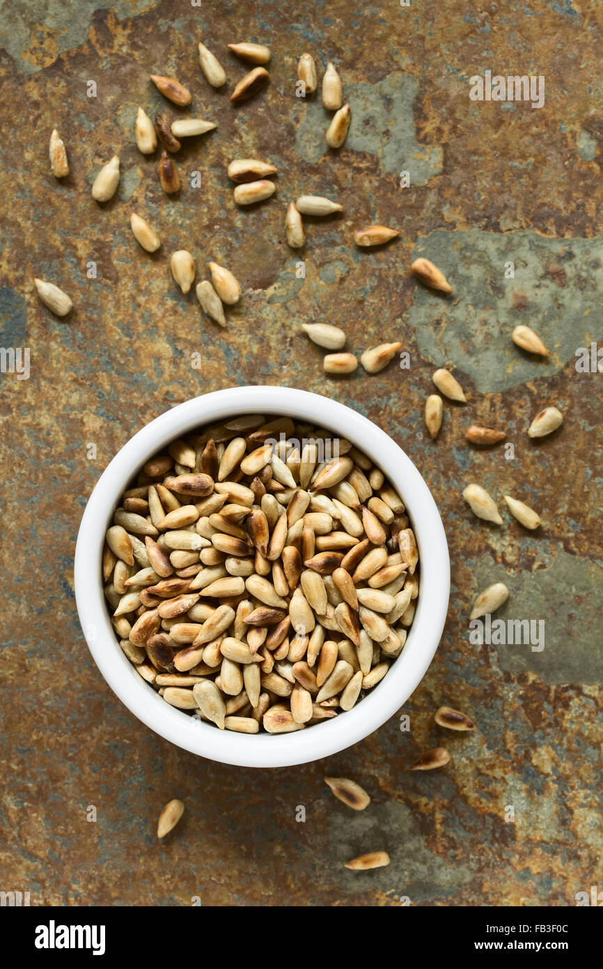 Roasted sunflower seeds in small bowl, photographed overhead on slate with natural light (Selective Focus) Stock Photo