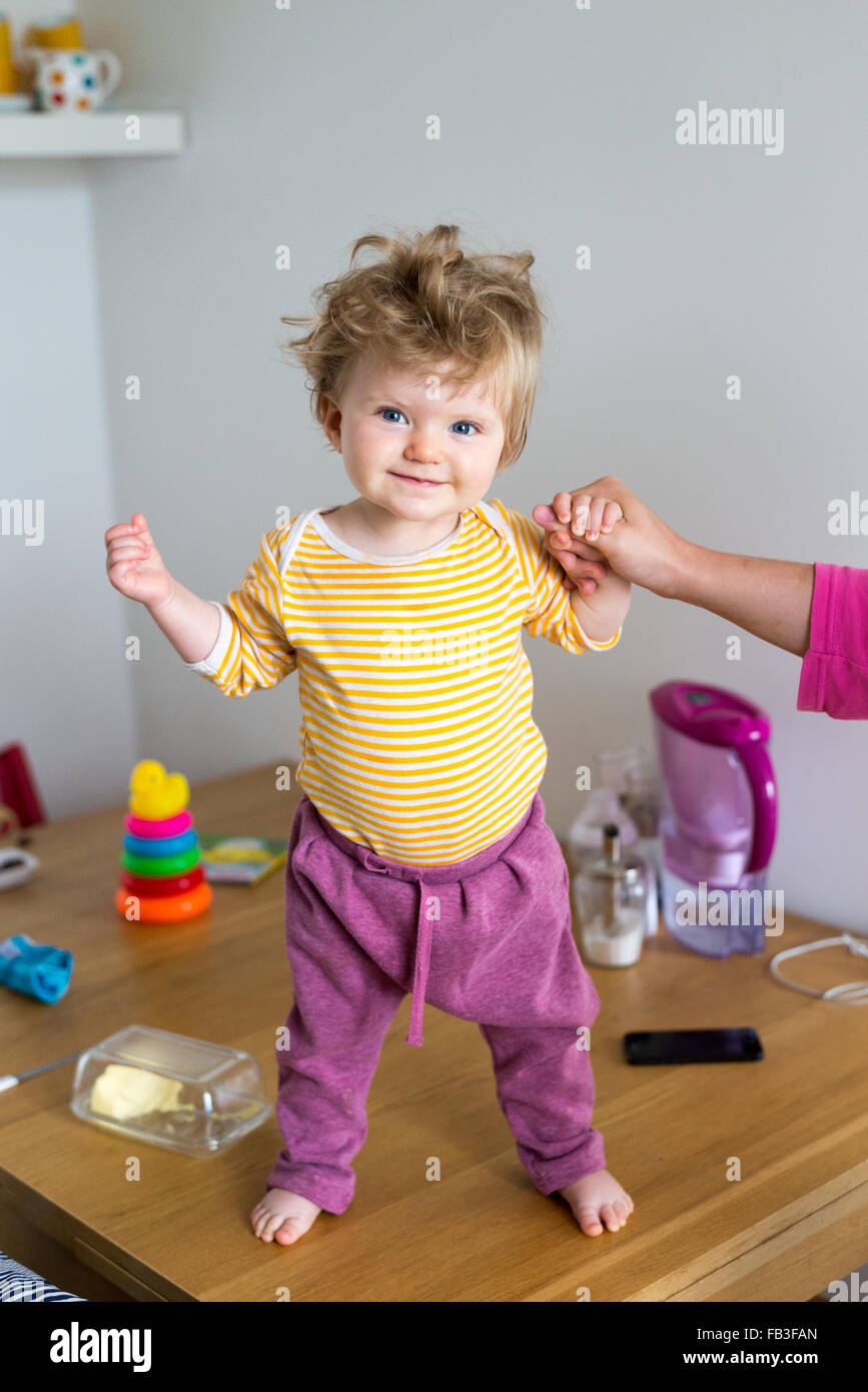 One year old baby standing up on table Stock Photo