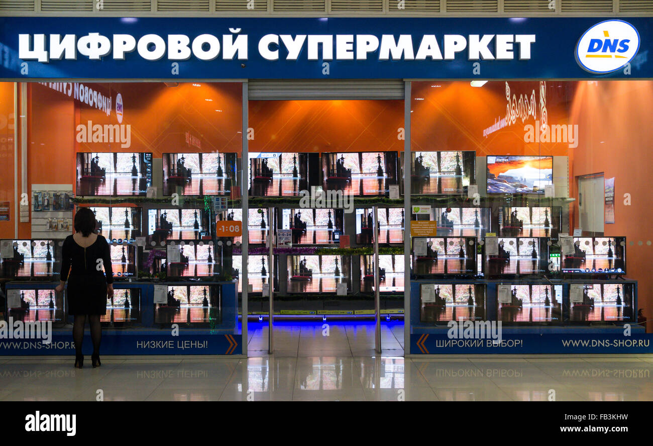 UFA - RUSSIA 19TH DECEMBER 2015 - Single woman in a black dress stares into a Russian television store called DNS in Ufa, Russia Stock Photo