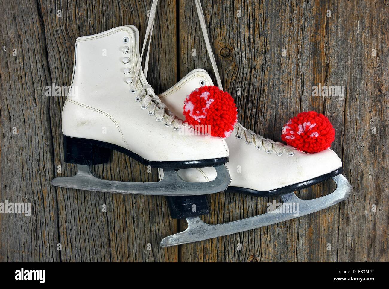 Pair of white ice skate with red yarn pompoms Stock Photo
