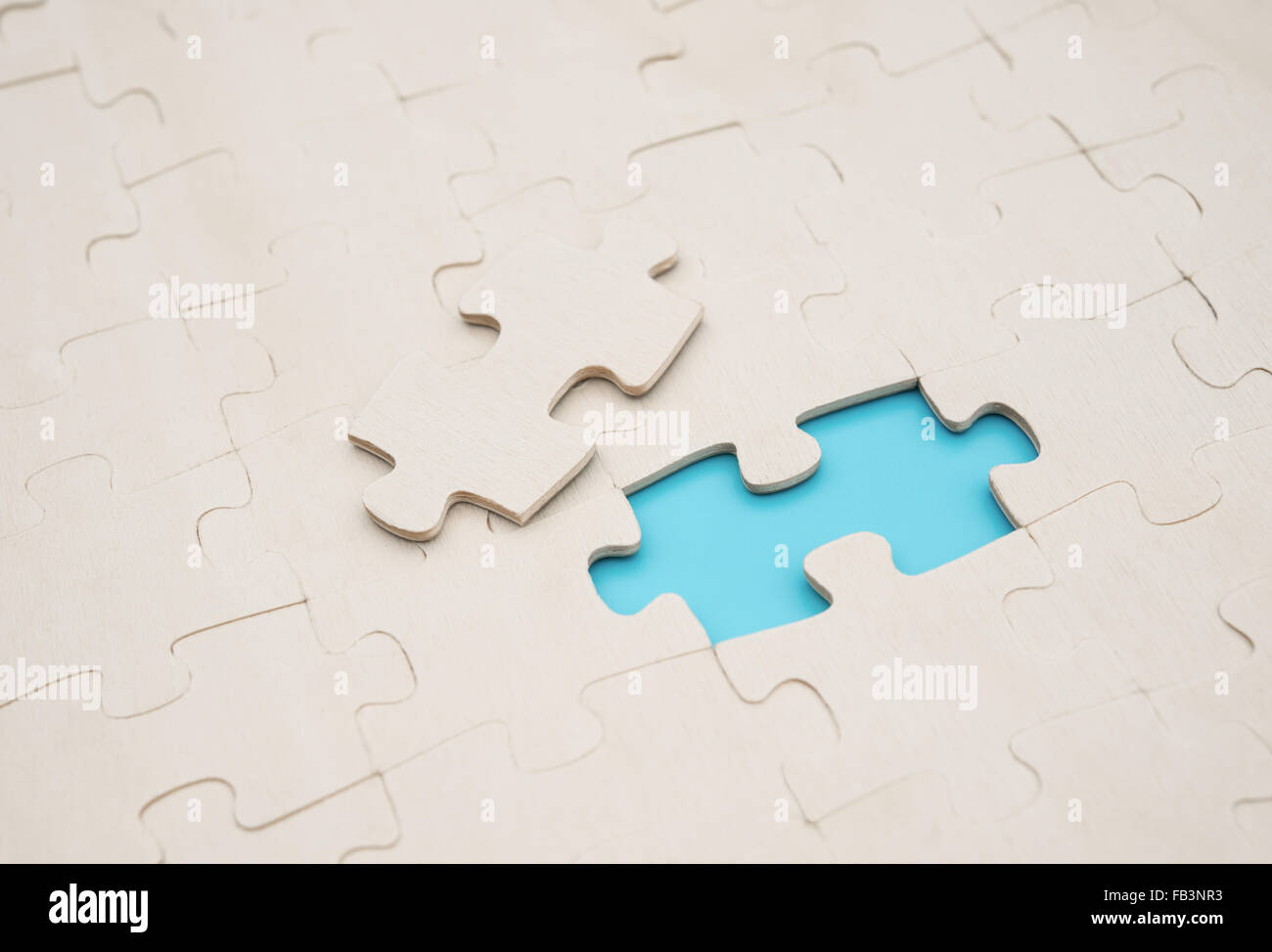 jigsaw puzzle with one piece separated on blue background Stock Photo