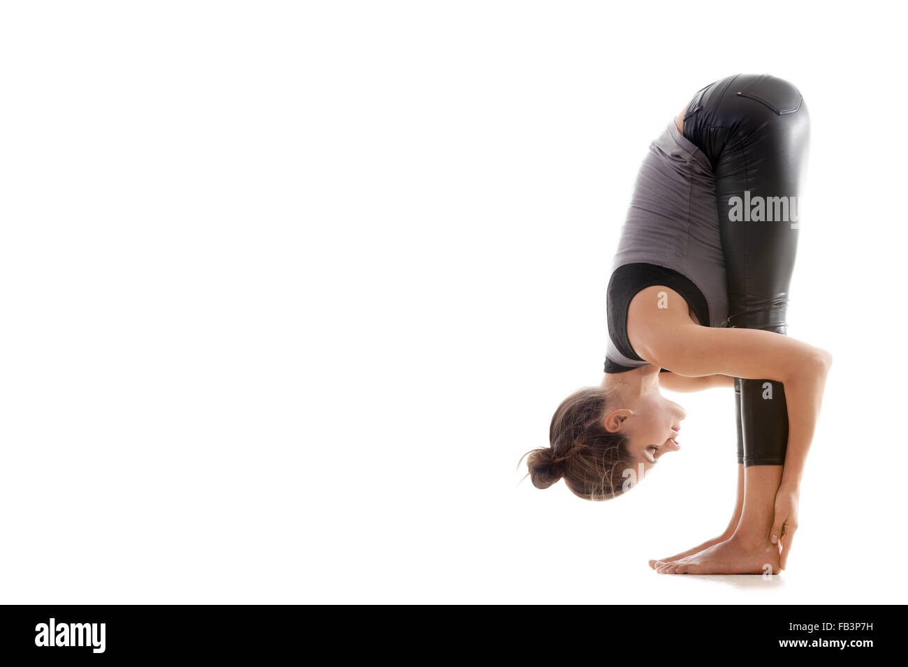 Sporty yoga girl on white background in uttanasana (Intense Forward-Bending Pose, Intense Stretch Pose, Forward Bend, Forward Fo Stock Photo
