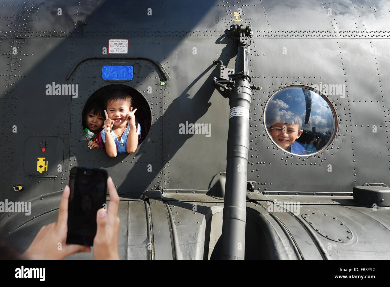 (160109) -- BANGKOK, Jan. 9. 2016 (Xinhua) -- Children look through the portholes of a helicopter during a public opening event marking the Thai Children' s Day at the Royal Thai Army 2nd Cavalry Division based in the north of downtown Bangkok, Thailand, Jan. 9, 2016. Thailand opened a number of its military bases to the public while the Thai Children' s Day is observed on the second Saturday in January. (Xinhua/Li Mangmang) Stock Photo