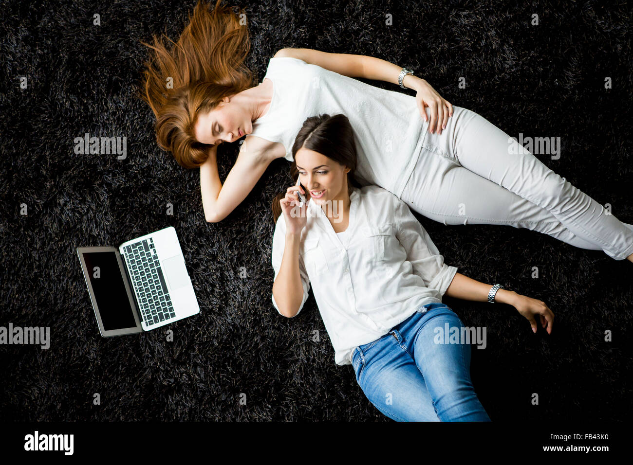 Young women laying on the carpet with laptop Stock Photo