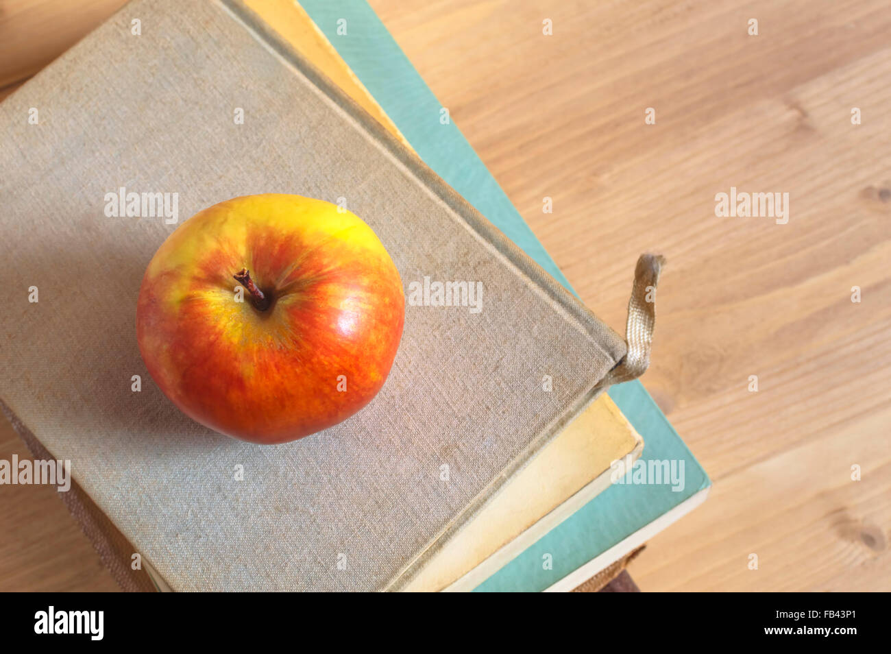 Stack of books and red apple on wooden table. Selective focus. Stock Photo