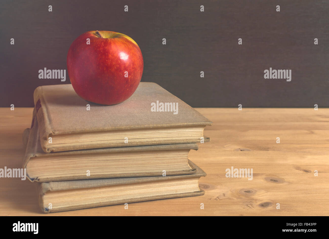 Stack of books and red apple on wooden table. Selective focus. Stock Photo